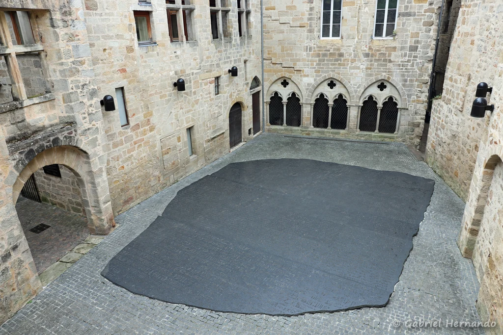 Place des écritures, au centre d'un cour médiévale, avec la reproduction de la pierre de Rosette, vue depuis le jardin supérieur (Figeac, juin 2022)